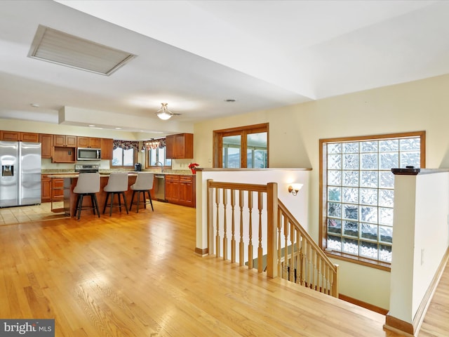 interior space featuring baseboards, a sink, light wood finished floors, and an upstairs landing