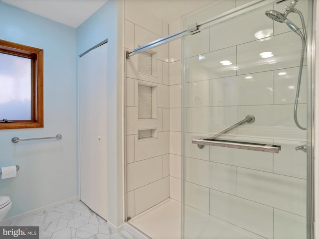 bathroom with toilet, a stall shower, and baseboards