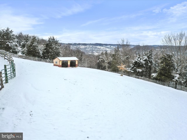 snowy yard featuring an outdoor structure and fence