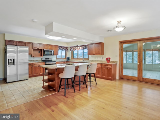 kitchen featuring a sink, appliances with stainless steel finishes, light wood-type flooring, open shelves, and a kitchen bar