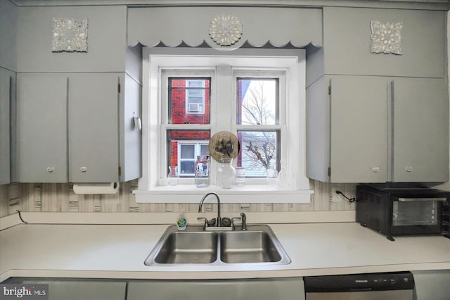 kitchen featuring stainless steel dishwasher, sink, and gray cabinetry