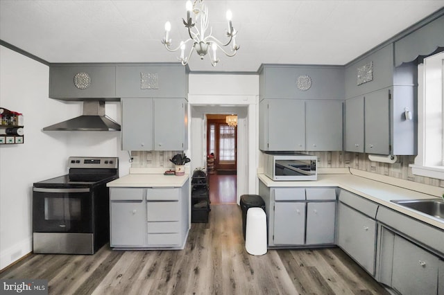 kitchen with wall chimney range hood, sink, gray cabinetry, stainless steel electric range oven, and dark hardwood / wood-style flooring