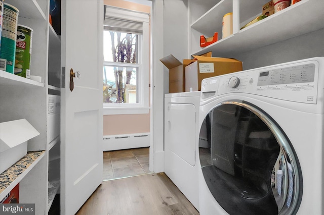 laundry room featuring washing machine and dryer, baseboard heating, and light hardwood / wood-style floors