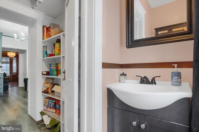 bathroom with an inviting chandelier, vanity, and wood-type flooring