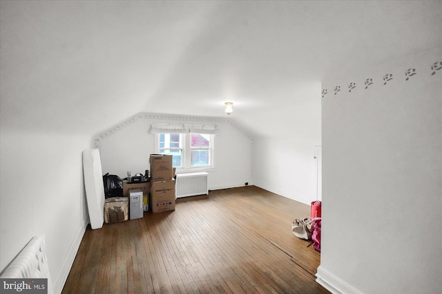 additional living space featuring hardwood / wood-style flooring, lofted ceiling, and radiator