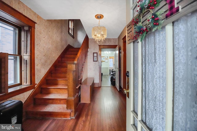 stairway with a wealth of natural light, a chandelier, and wood-type flooring