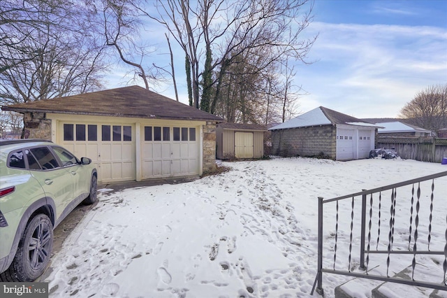 yard covered in snow with a garage and a shed