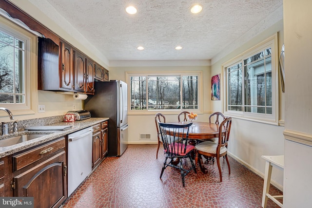 kitchen featuring appliances with stainless steel finishes, dark brown cabinets, sink, and a textured ceiling