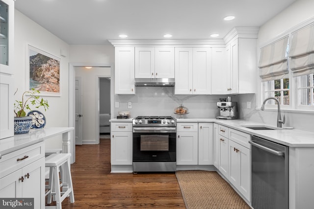 kitchen with dark wood-type flooring, sink, white cabinetry, light stone counters, and stainless steel appliances