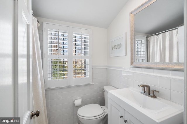 bathroom featuring vanity, toilet, and tile walls