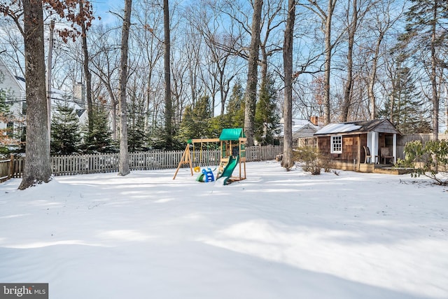 snowy yard with an outdoor structure and a playground