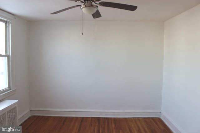 empty room featuring dark wood-type flooring and radiator heating unit