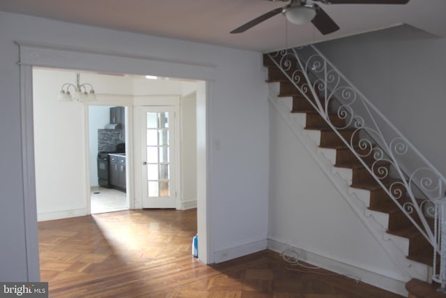 stairs featuring ceiling fan with notable chandelier and parquet flooring