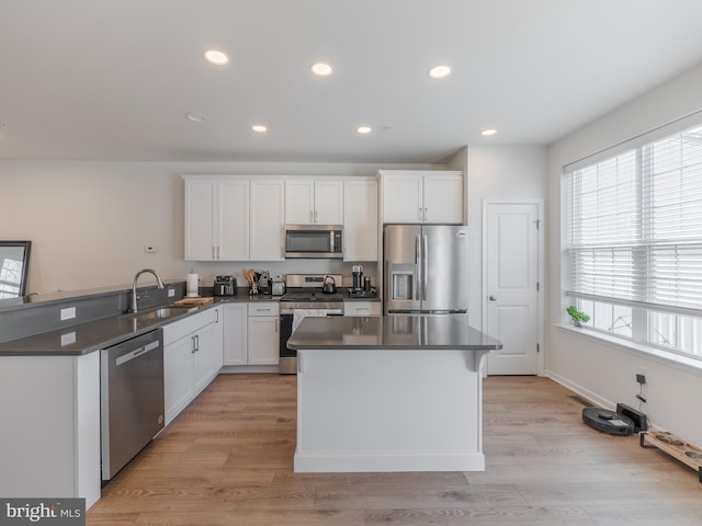 kitchen with sink, light hardwood / wood-style flooring, stainless steel appliances, white cabinets, and kitchen peninsula