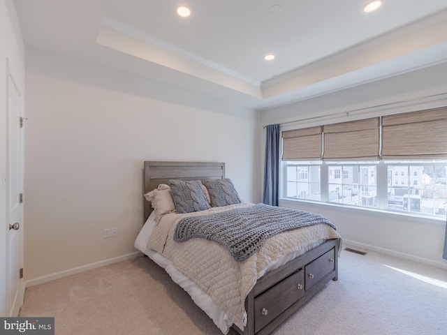 bedroom with crown molding, light colored carpet, and a raised ceiling