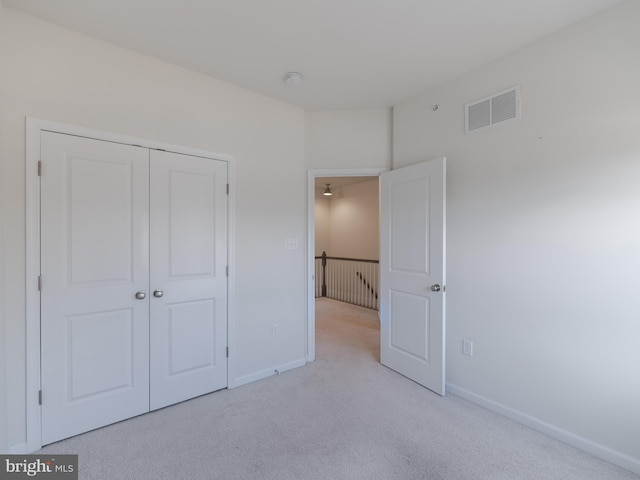 unfurnished bedroom with light carpet and a closet