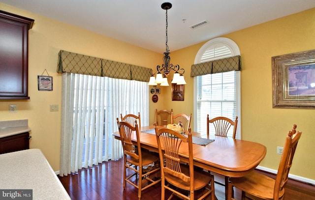 dining space featuring dark wood-type flooring and a chandelier