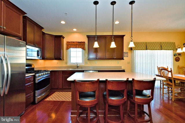 kitchen featuring a kitchen island, appliances with stainless steel finishes, sink, and pendant lighting