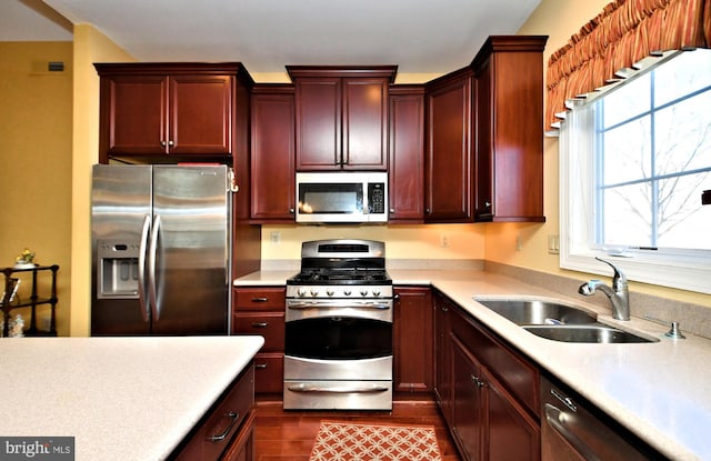 kitchen with appliances with stainless steel finishes, dark hardwood / wood-style flooring, and sink