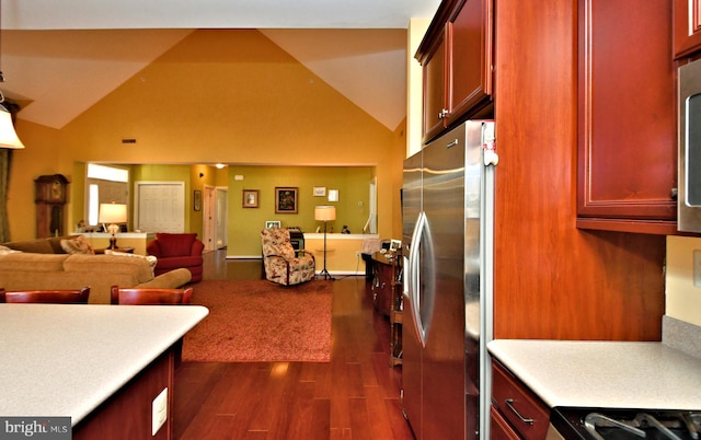 kitchen featuring high vaulted ceiling, range, stainless steel fridge, and dark hardwood / wood-style flooring