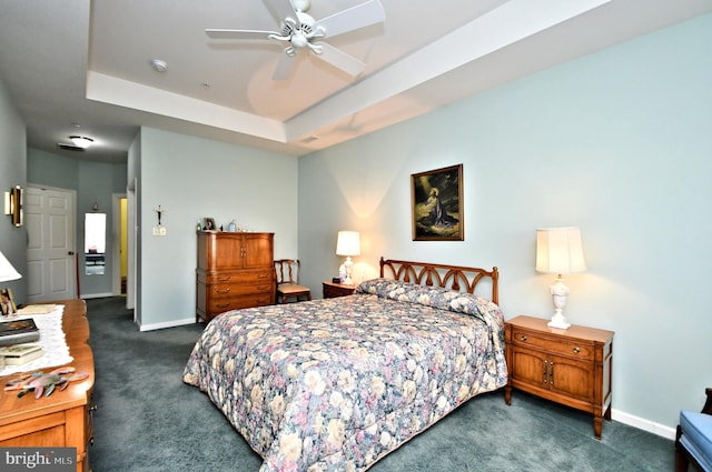 bedroom with ceiling fan, a tray ceiling, and dark colored carpet