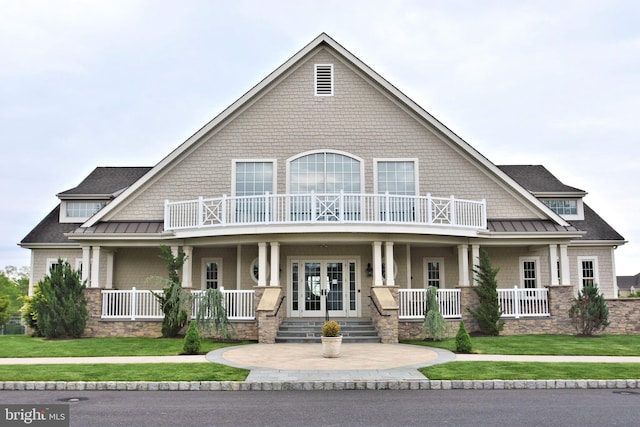 view of front of house with a balcony, a front yard, and covered porch