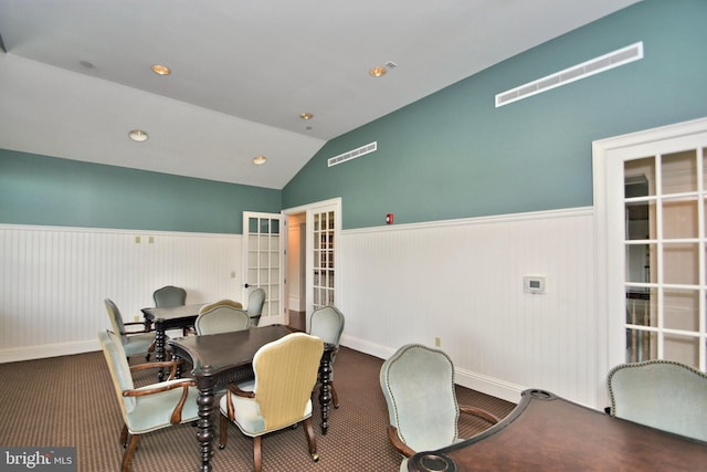 carpeted dining room featuring vaulted ceiling and french doors