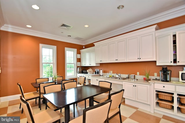 kitchen with white cabinetry, crown molding, and sink