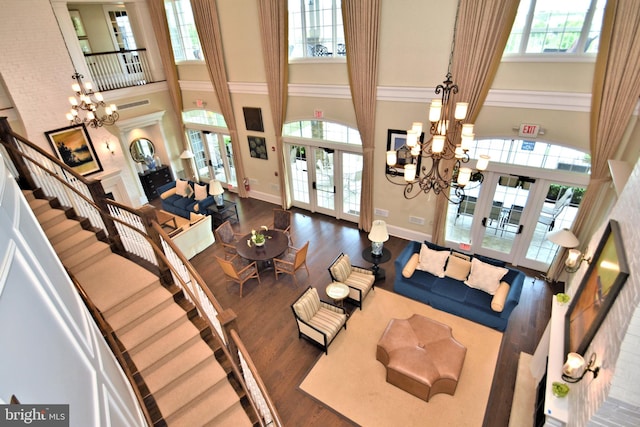 living room with french doors, a towering ceiling, dark hardwood / wood-style flooring, and a notable chandelier