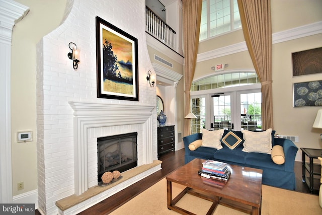 living room with dark hardwood / wood-style floors, a towering ceiling, a fireplace, and french doors