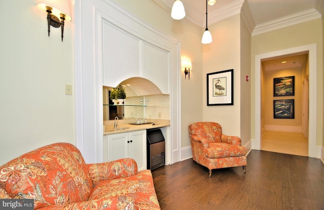 sitting room featuring ornamental molding, dark wood-type flooring, and wet bar