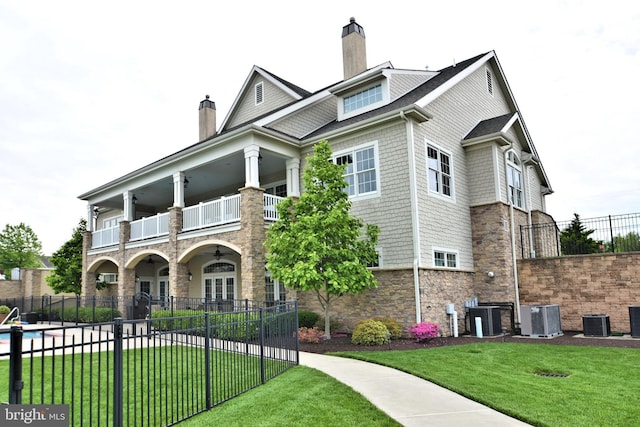 view of front of home with central AC, a balcony, and a front yard