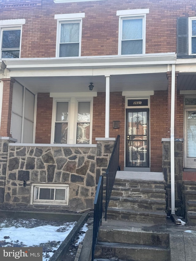 snow covered property entrance featuring covered porch