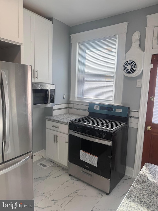 kitchen with white cabinetry, stainless steel appliances, and light stone counters