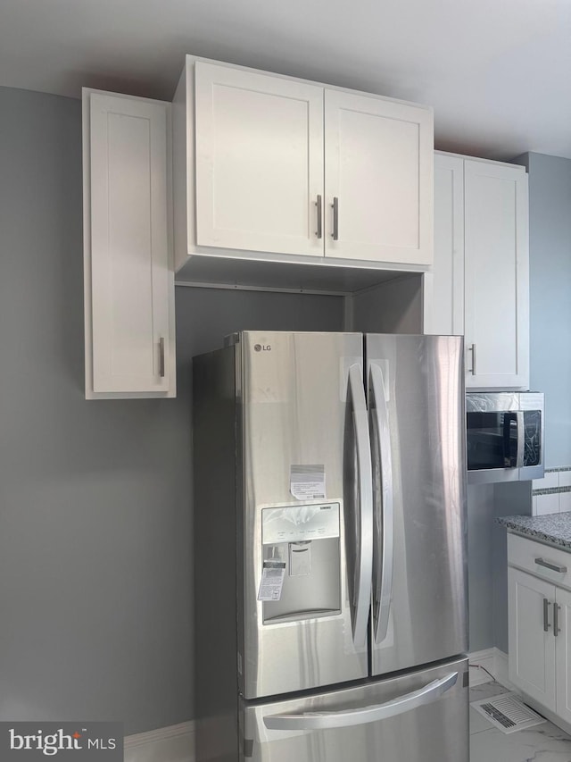 kitchen with white cabinetry, appliances with stainless steel finishes, and light stone countertops