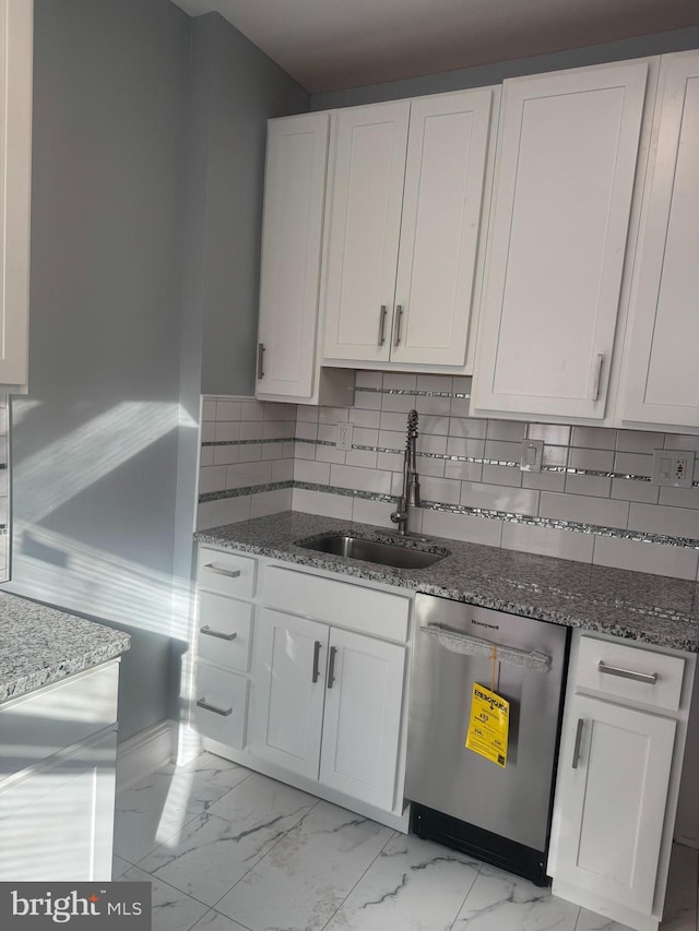 kitchen featuring sink, white cabinetry, dishwashing machine, dark stone counters, and backsplash