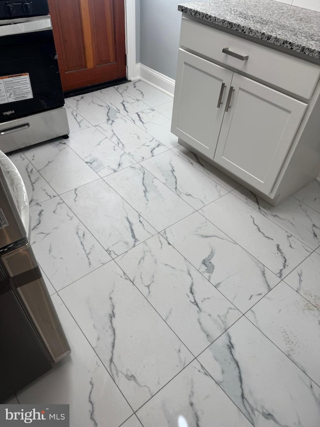 room details featuring white cabinetry, light stone counters, and stainless steel gas stove