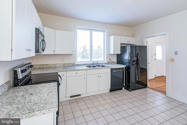 kitchen featuring sink, light tile patterned floors, black appliances, and white cabinets