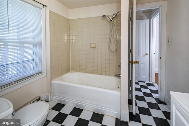 bathroom featuring a wealth of natural light, toilet, and tiled shower / bath