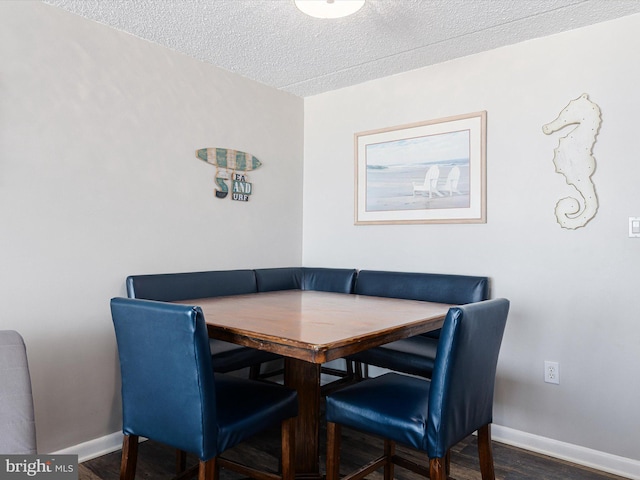 dining room featuring breakfast area, dark wood-type flooring, and a textured ceiling