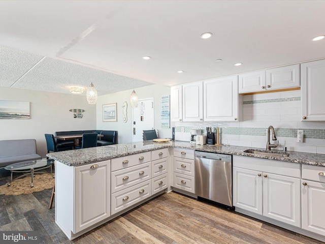 kitchen with pendant lighting, white cabinetry, dishwasher, sink, and kitchen peninsula