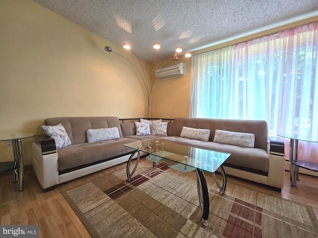 living room featuring wood-type flooring, a wall mounted AC, and a textured ceiling