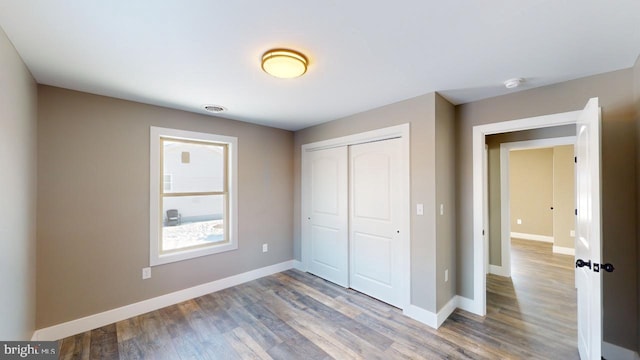 unfurnished bedroom with hardwood / wood-style flooring and a closet