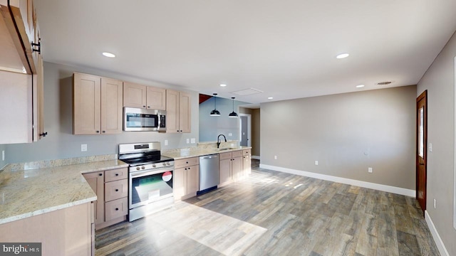 kitchen featuring appliances with stainless steel finishes, light brown cabinetry, sink, hanging light fixtures, and light hardwood / wood-style flooring