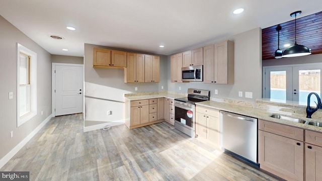 kitchen with appliances with stainless steel finishes, sink, pendant lighting, and light brown cabinetry