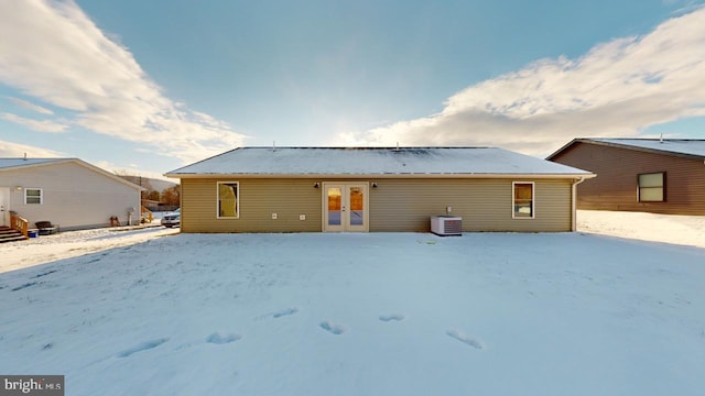 snow covered house with central AC unit and french doors