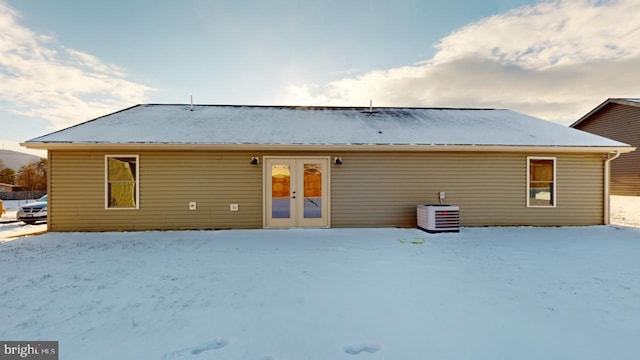 snow covered house with central AC unit and french doors