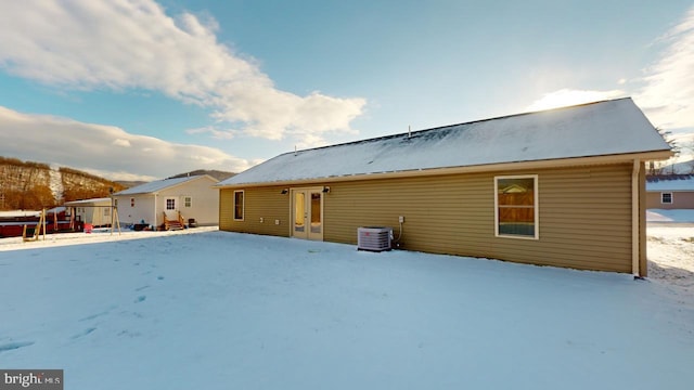 snow covered rear of property with central AC