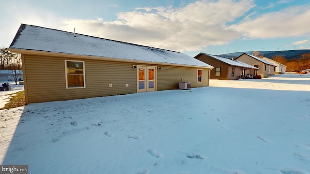 snow covered house with central AC and french doors