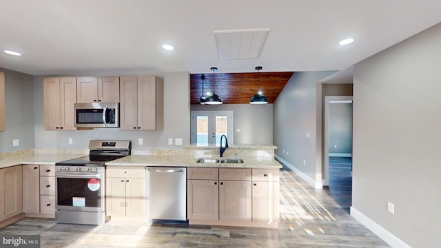 kitchen with appliances with stainless steel finishes, sink, hanging light fixtures, kitchen peninsula, and light brown cabinets